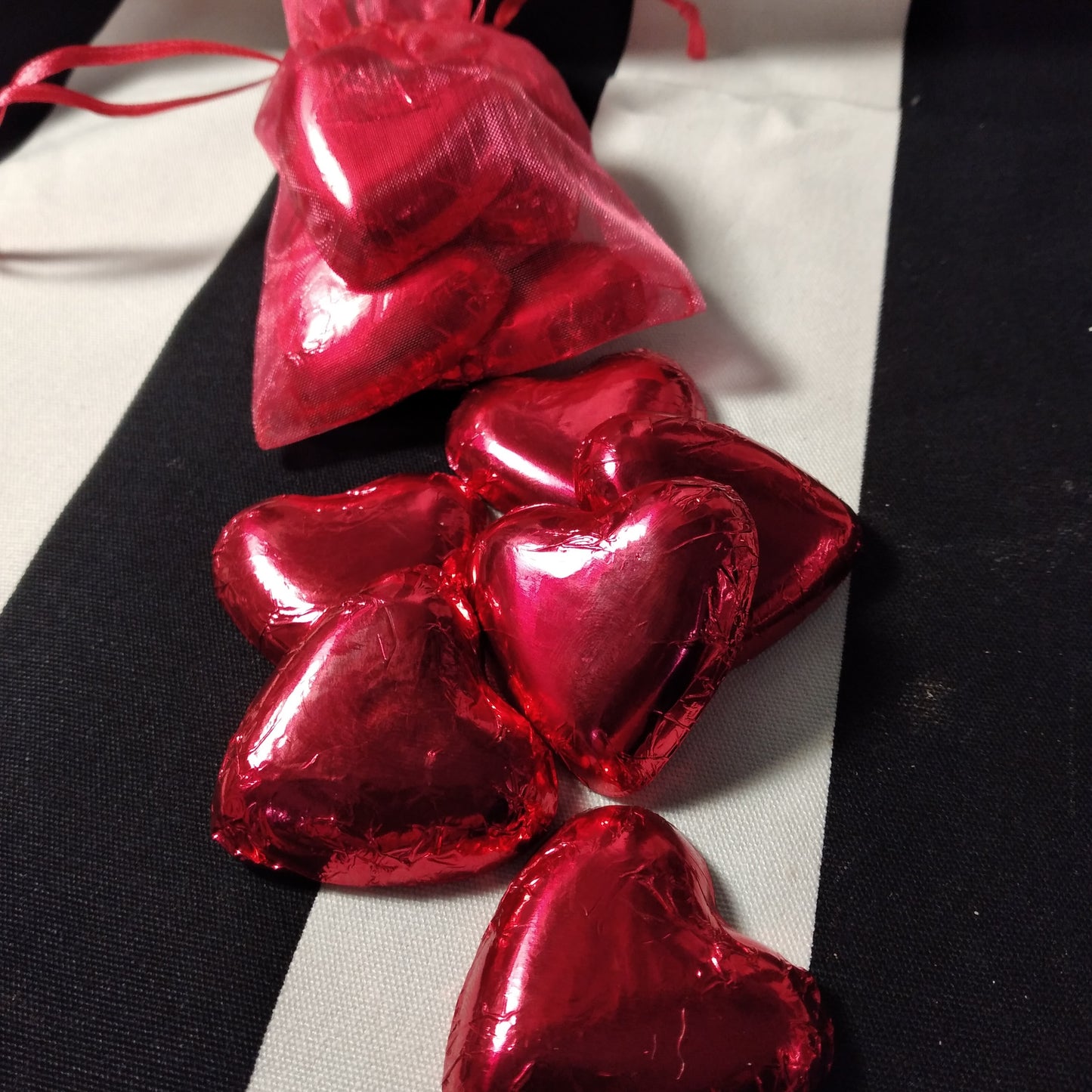 Six cœurs de Saint-Valentin en chocolat enveloppés dans du papier d'aluminium.