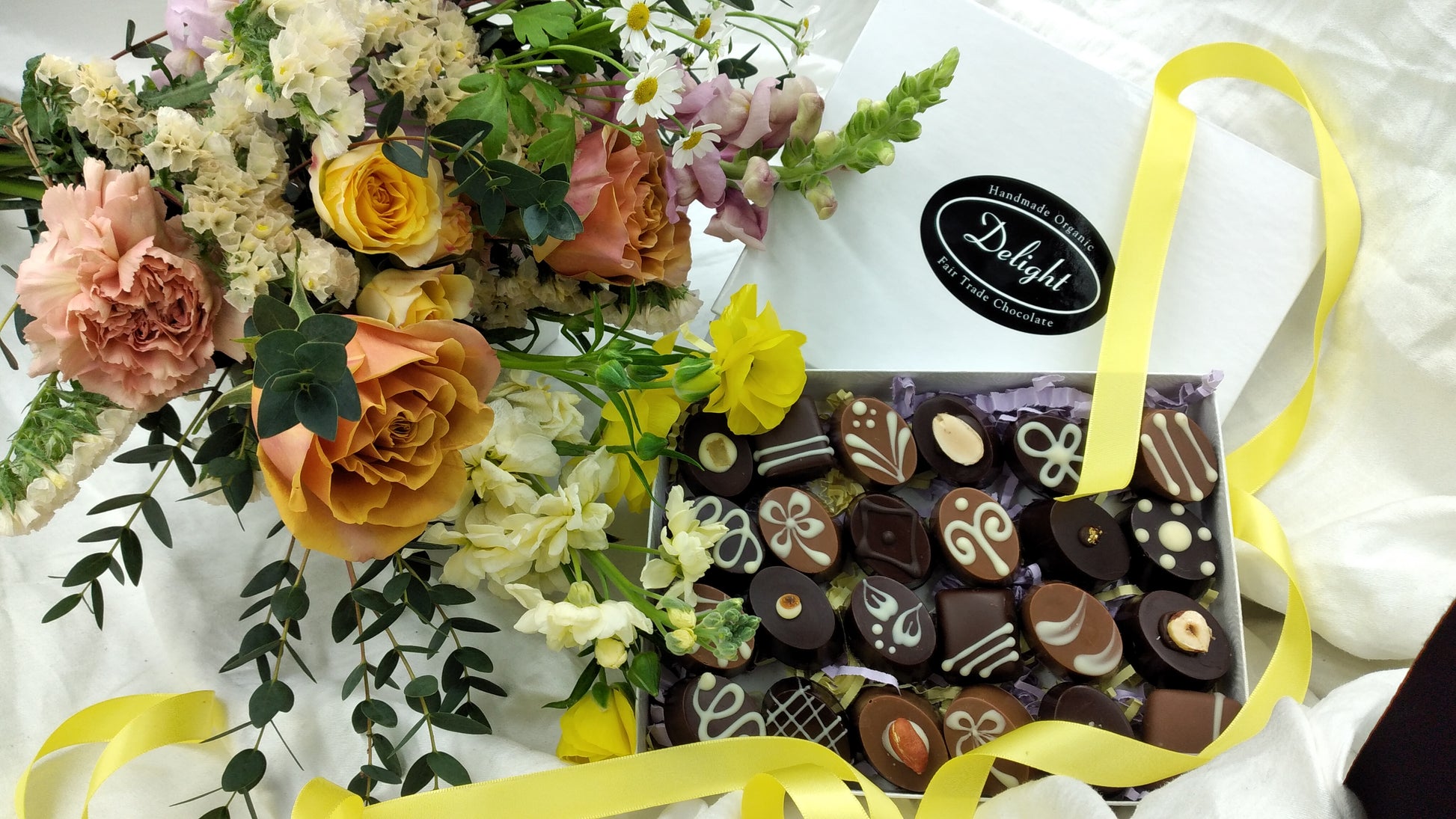 Gift box of artisan hand decorated organic chocolates with bunch of flowers